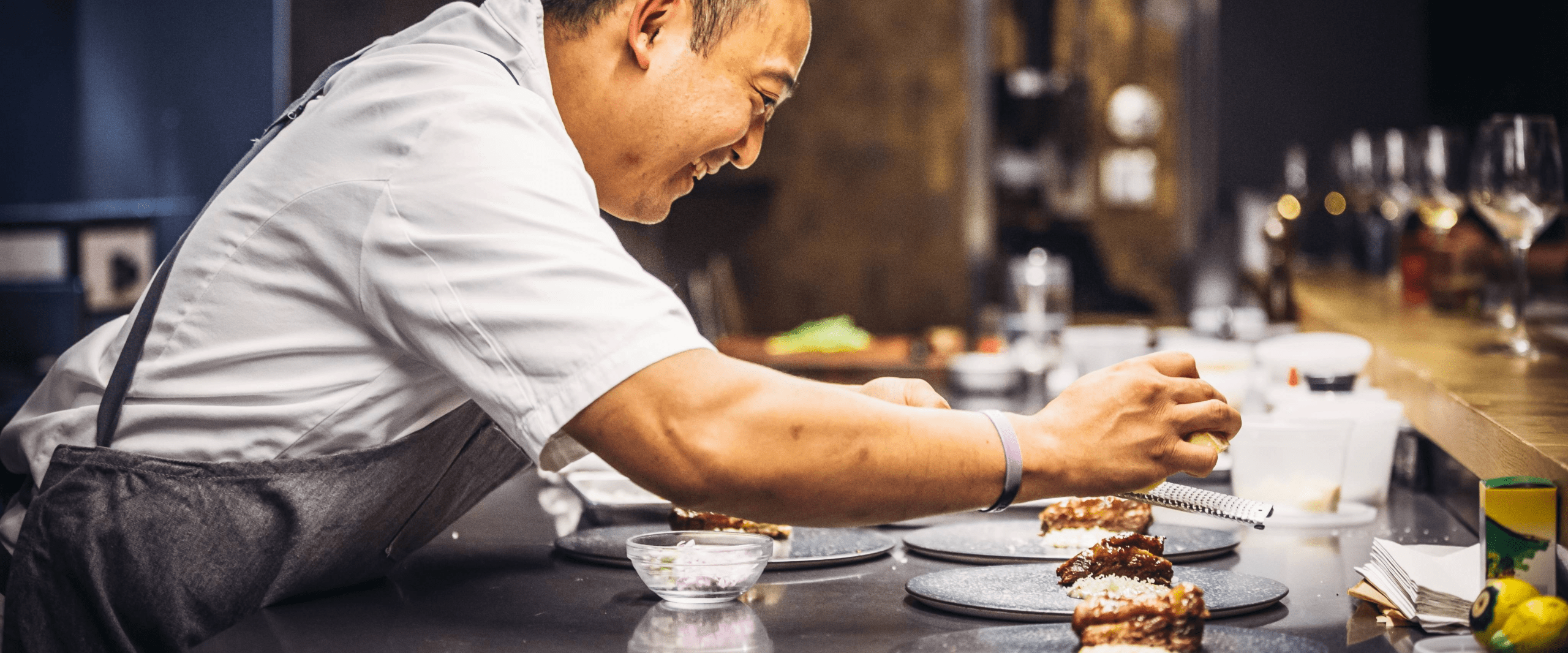 A chef slices a cheese pizza in kitchen