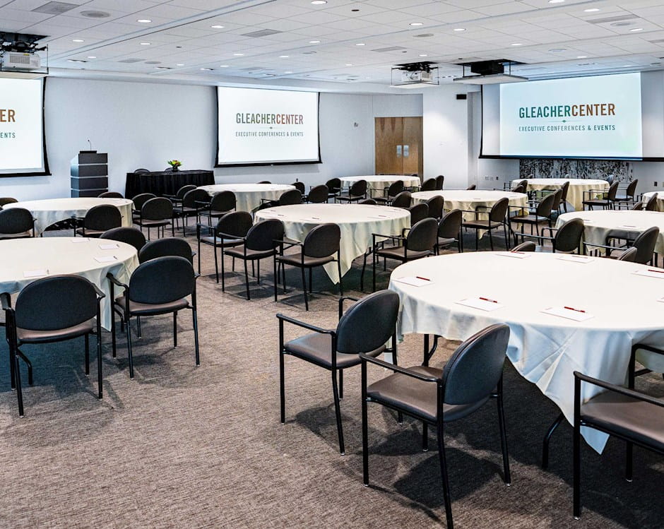 Gleacher Center conference area staged for event with projectors, tables, and chairs with notepads