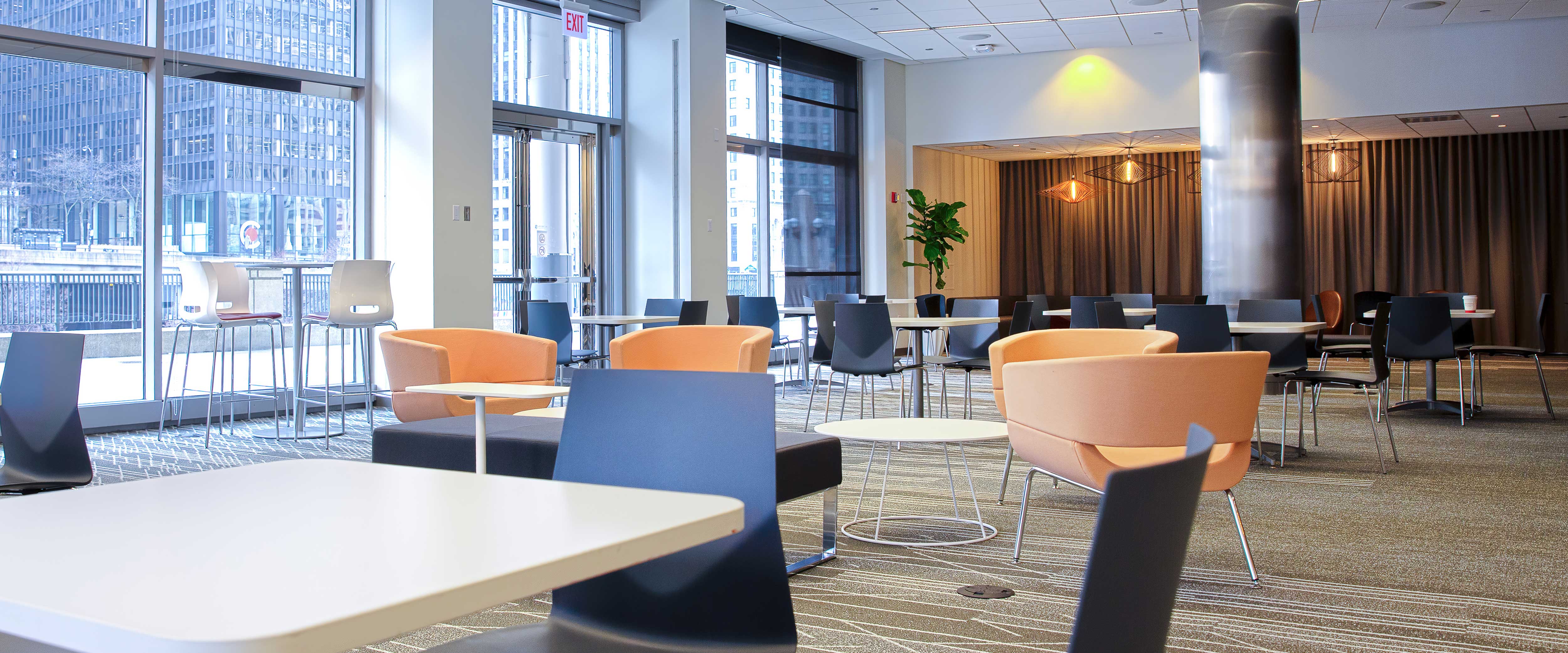 Lobby Lounge in Gleacher Center with a set of table and chairs toward a brown fabric feature wall and wall of floor-to-ceiling windows