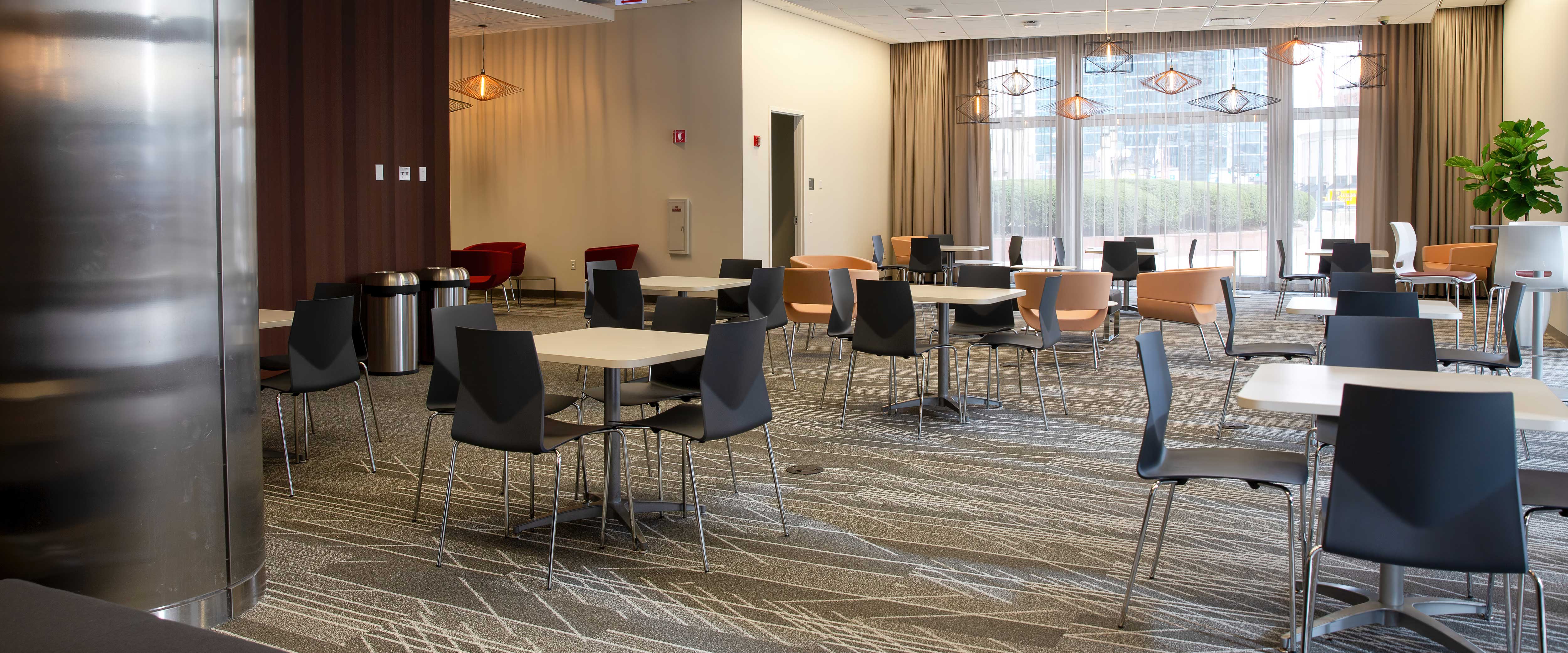 Gleacher Center lobby filled with square tables surrounded by chairs looking toward an inviting window