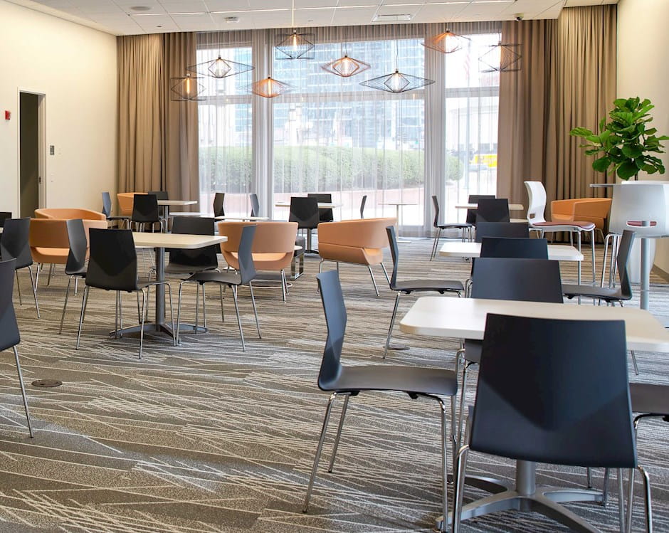 Gleacher Center lobby filled with square tables surrounded by chairs looking toward an inviting window