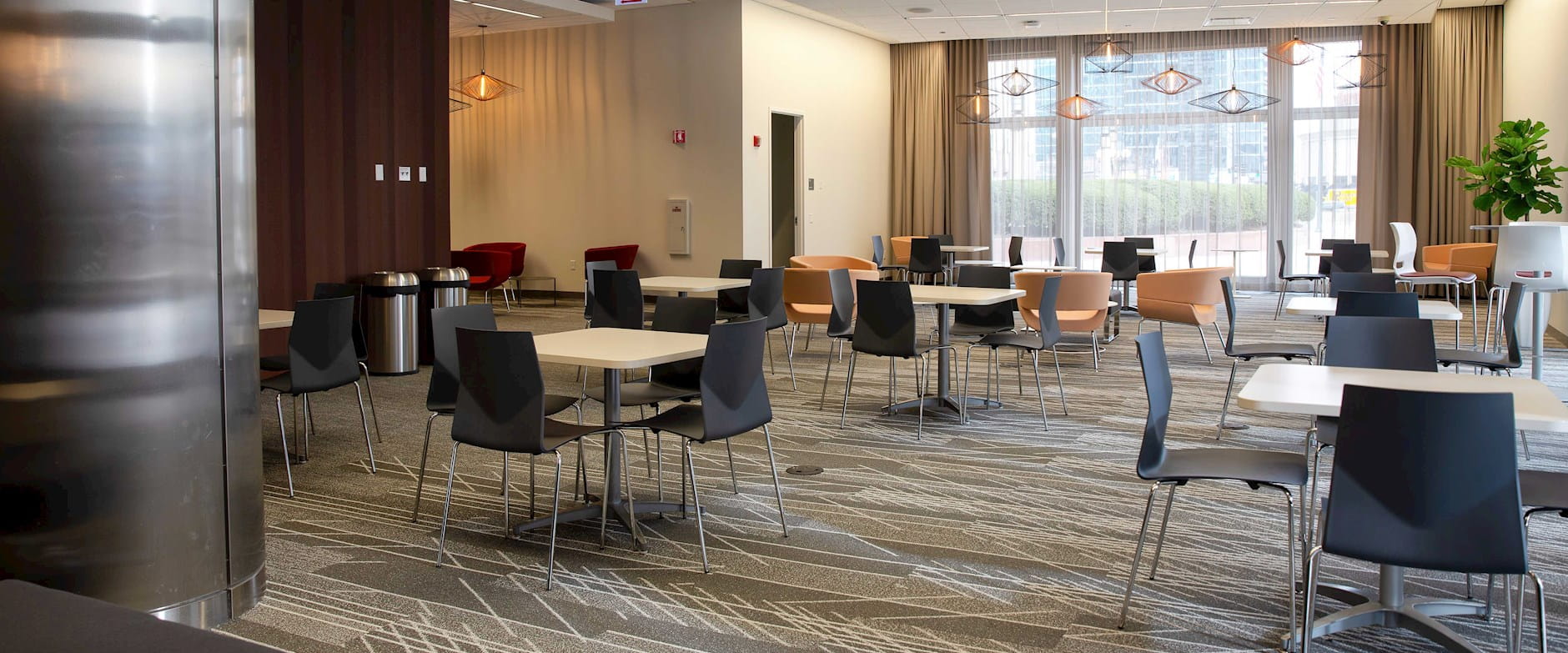 Gleacher Center lobby filled with square tables surrounded by chairs looking toward an inviting window