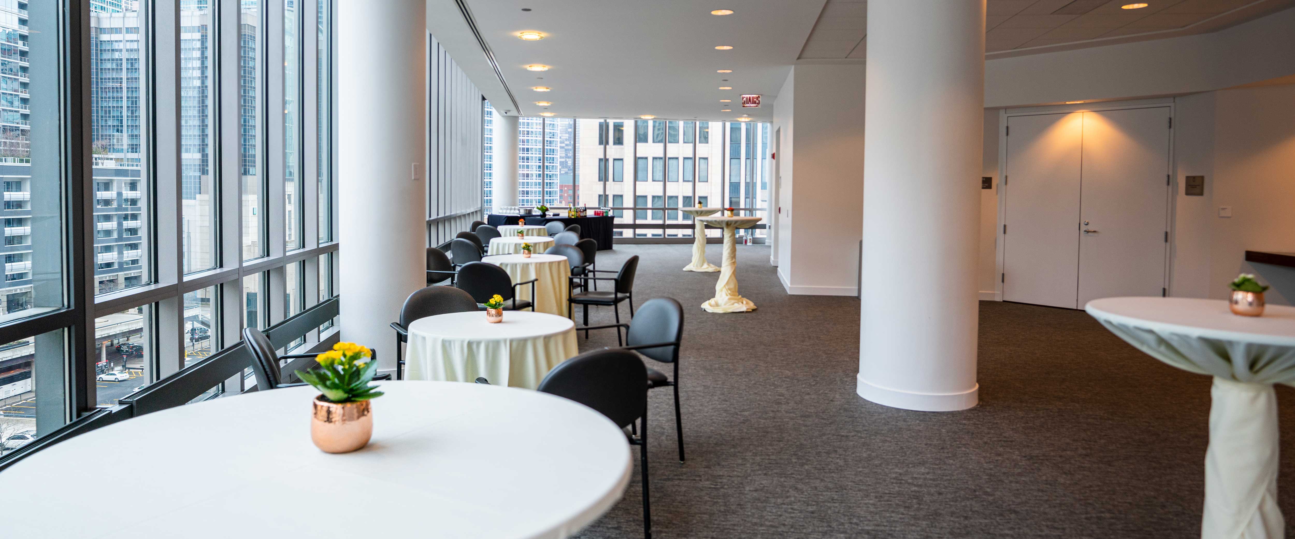 Set tables with flower center pieces in room 650 in the Gleacher Center
