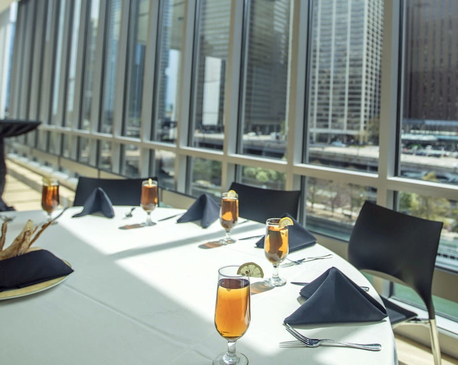 Lounge at the Gleacher Center with dining table set with glasses and napkins looking south over the Chicago River