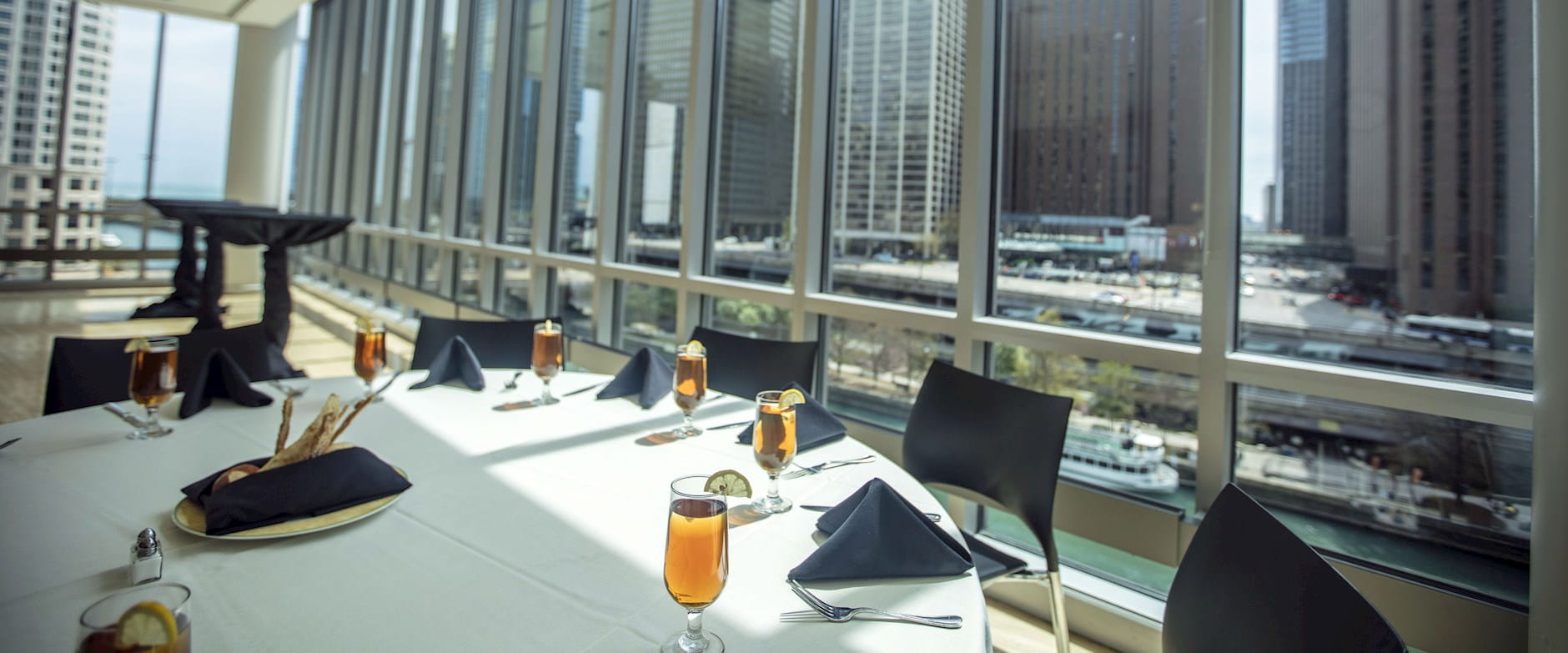 Lounge at the Gleacher Center with dining table set with glasses and napkins looking south over the Chicago River