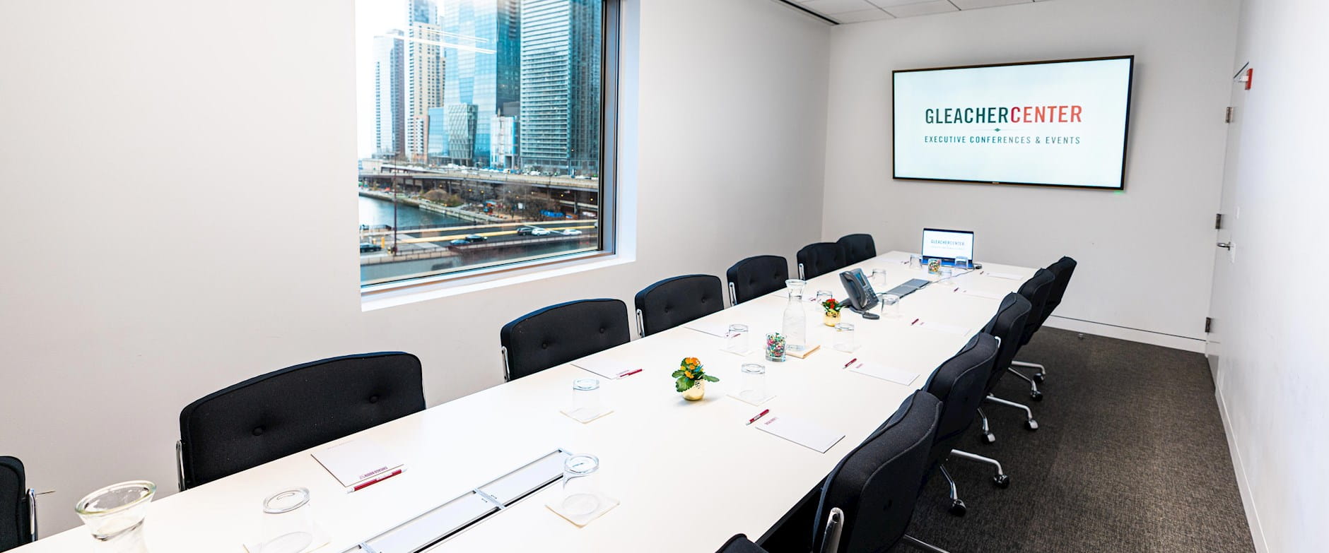 Set boardroom table in the Gleacher Center with a presentation screen and laptop
