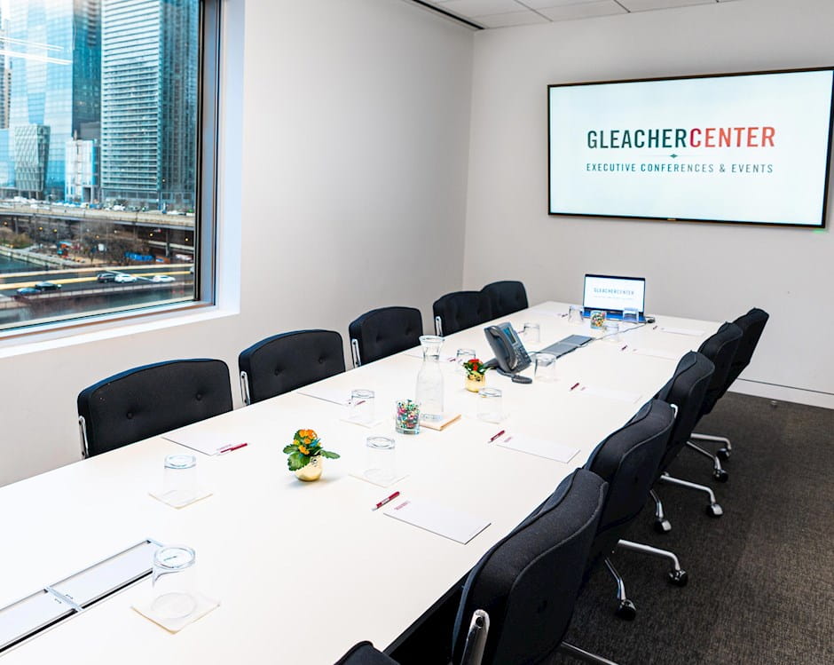 Set boardroom table in the Gleacher Center with a presentation screen and laptop