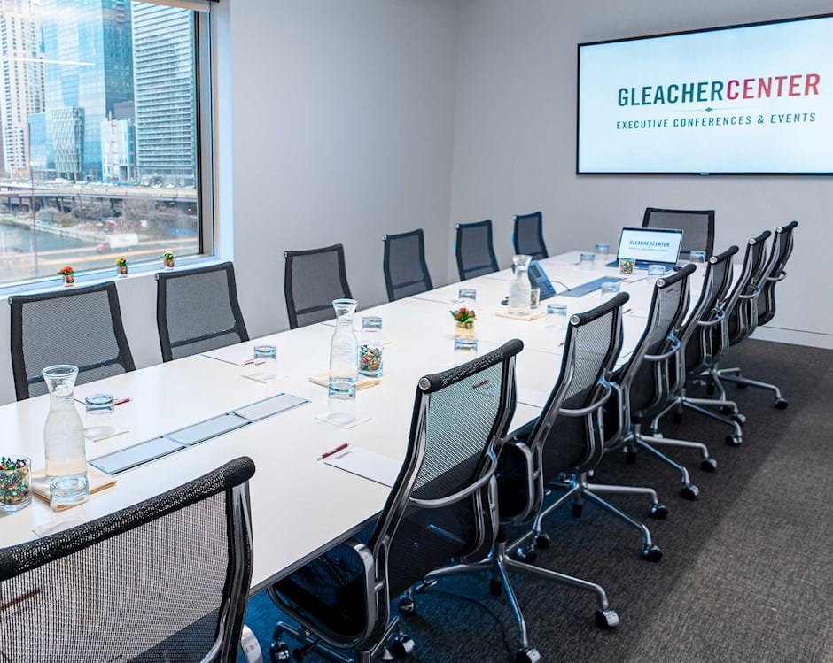 Long boardroom table in the Gleacher Center with a window overlooking the Chicago River