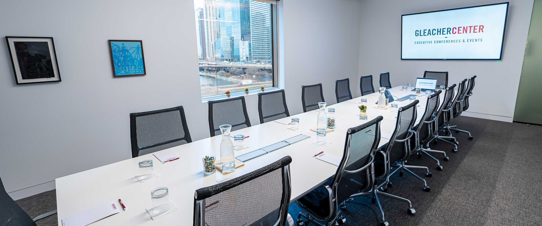 Long boardroom table in the Gleacher Center with a window overlooking the Chicago River