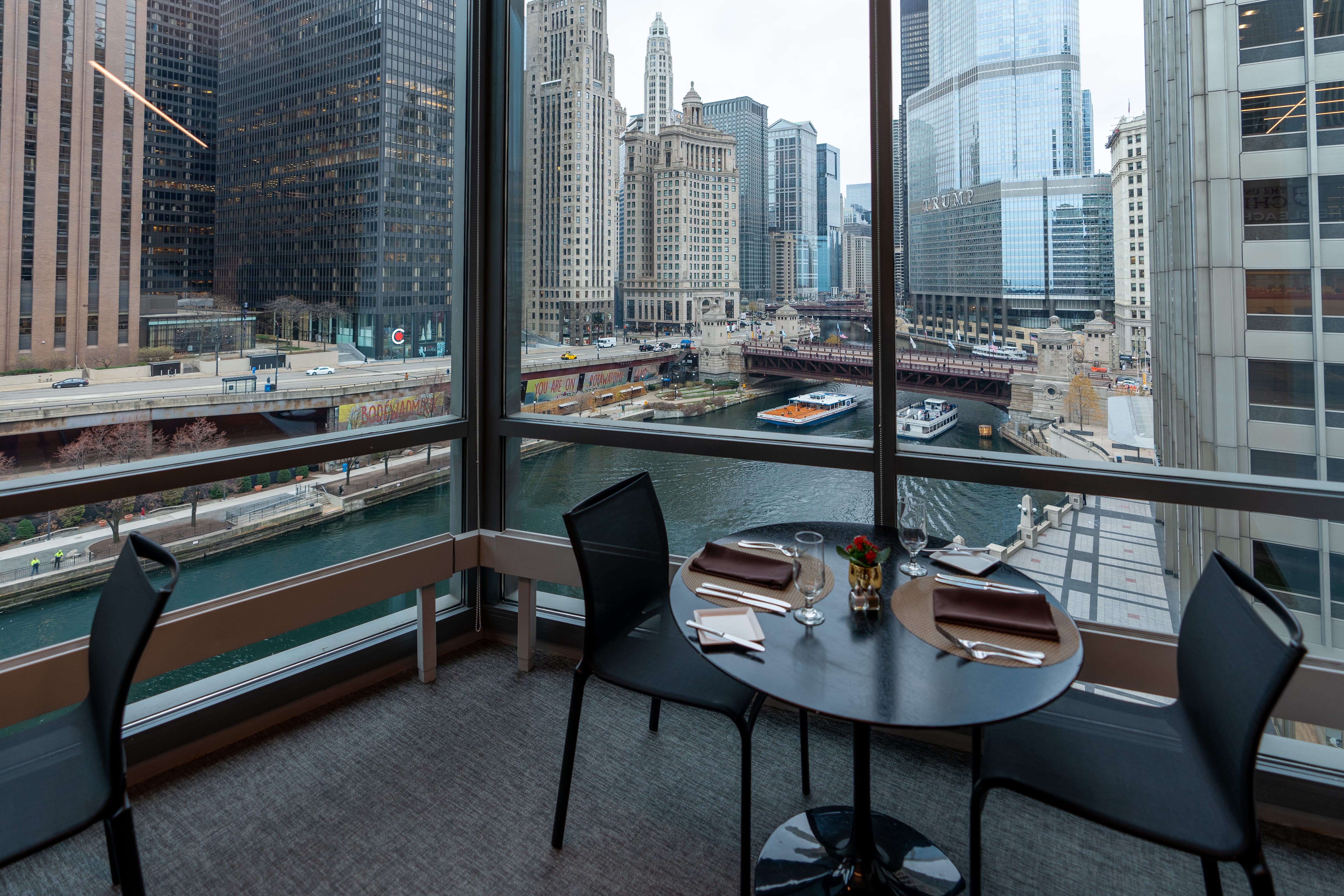 Close up view of two-person dining table overlooking Chicago river. View from inside PIMCO Midway Club.