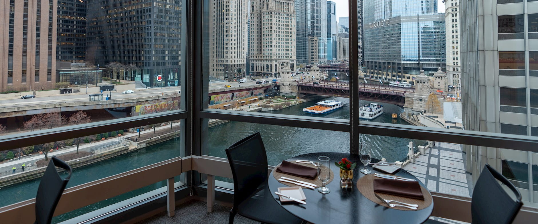 Close up view of two-person dining table overlooking Chicago river. View from inside PIMCO Midway Club.