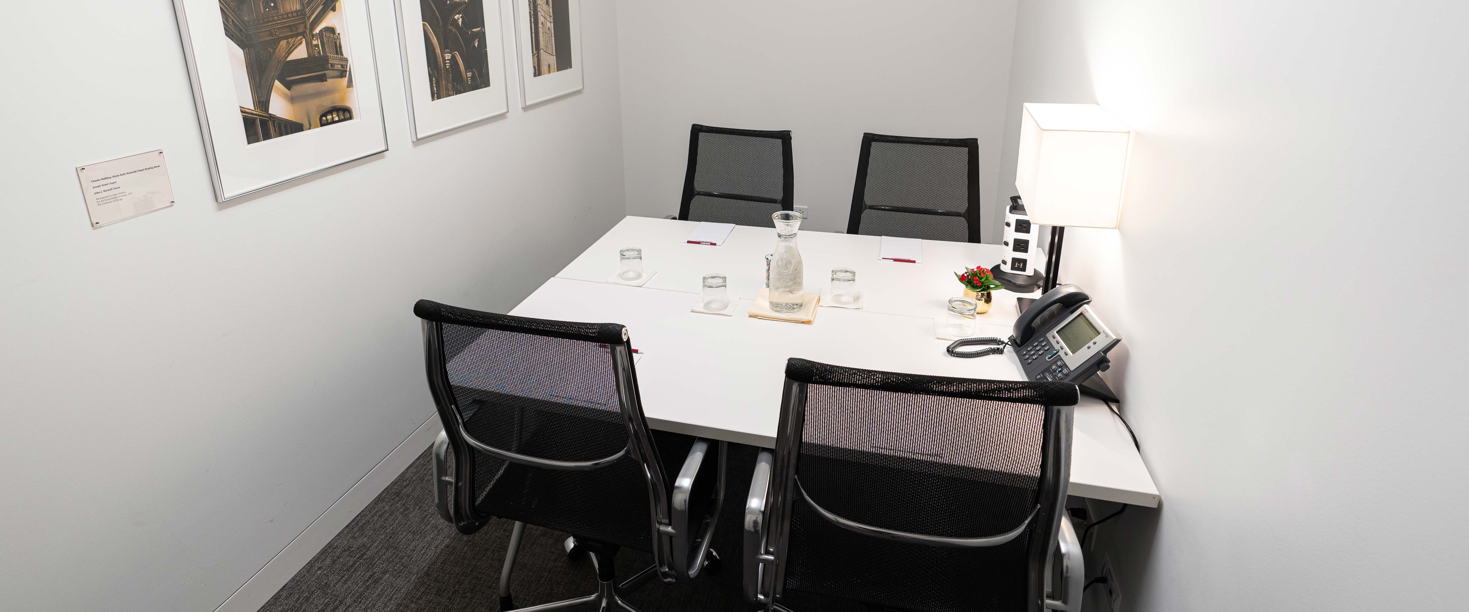 PIMCO small executive board room with 4-person table set with water, notepads, and outlets