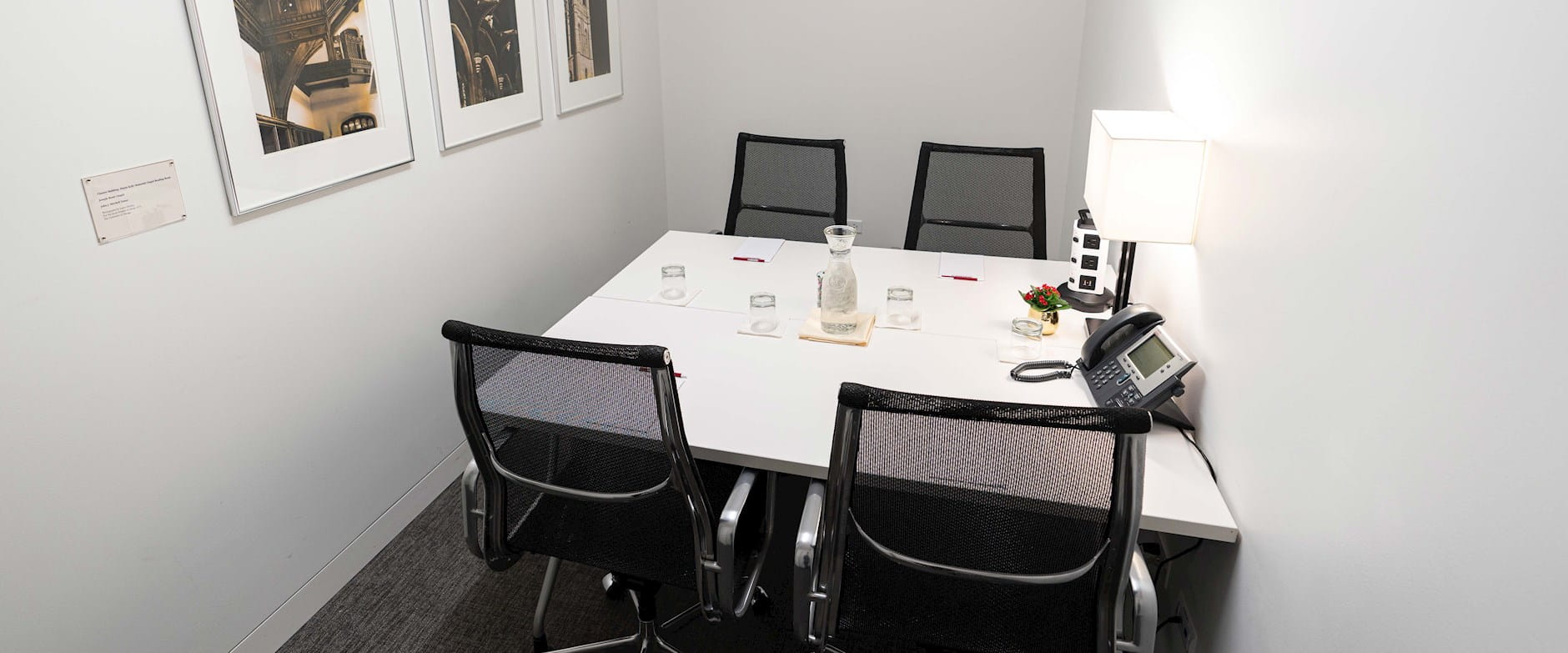 PIMCO small executive board room with 4-person table set with water, notepads, and outlets