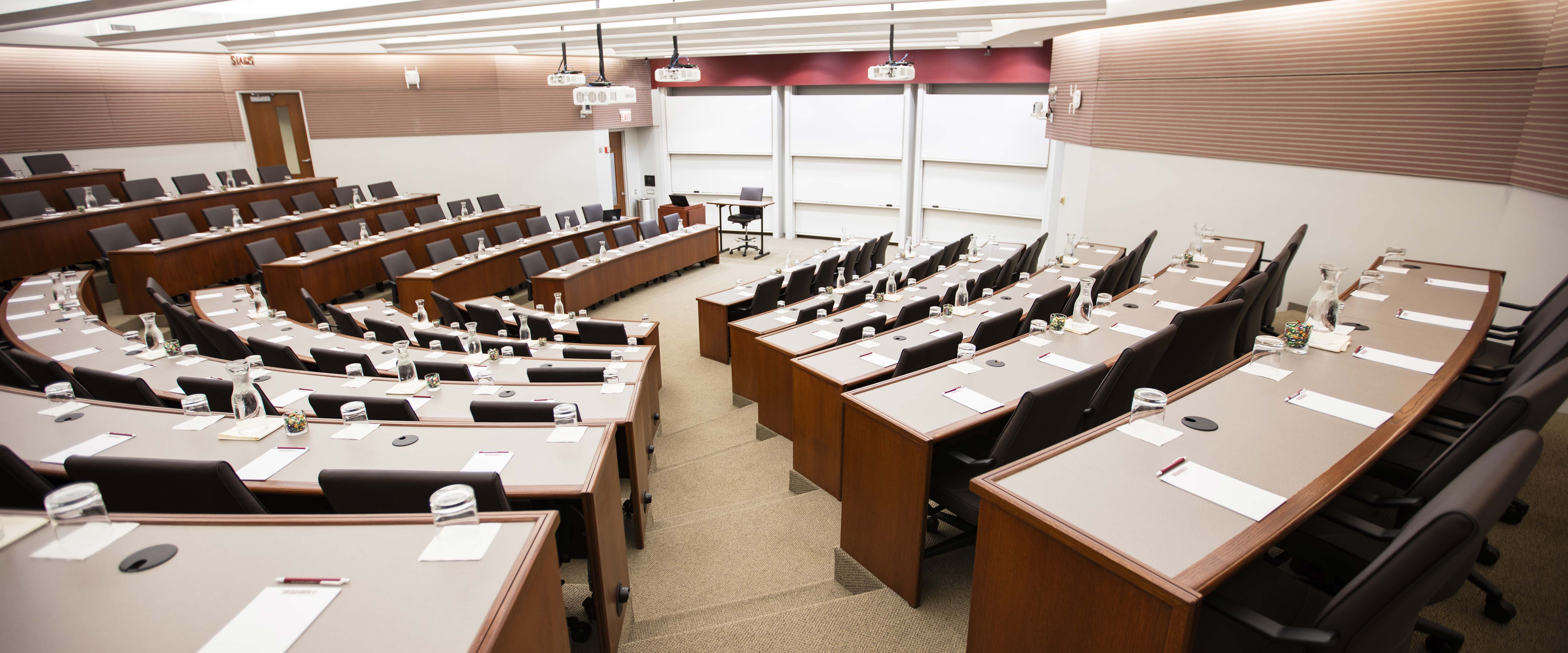Gleacher Center room 100 from the back of the classroom looking down at tiered tables and chairs in a semi-circle