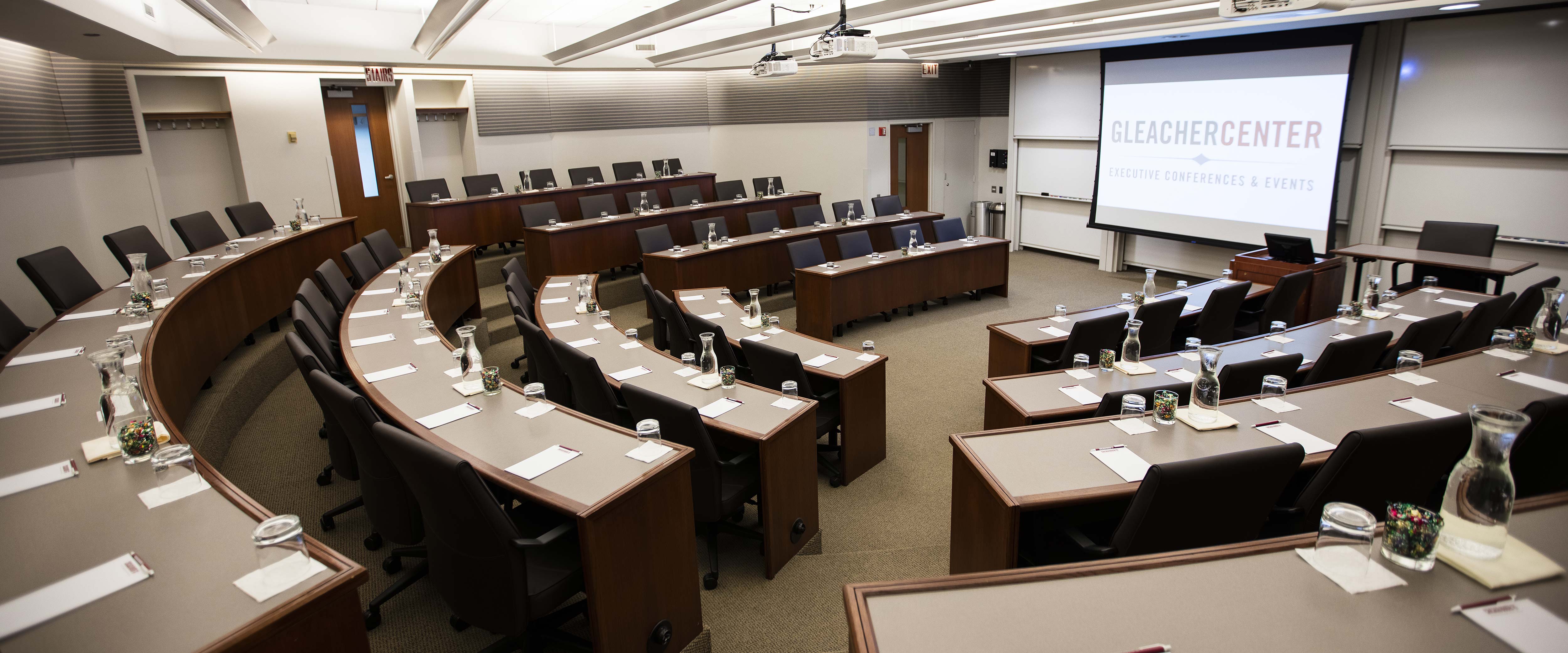 A view of the Gleacher Center room 406 from the back looking down on tiered tables and chairs in a semi-circle