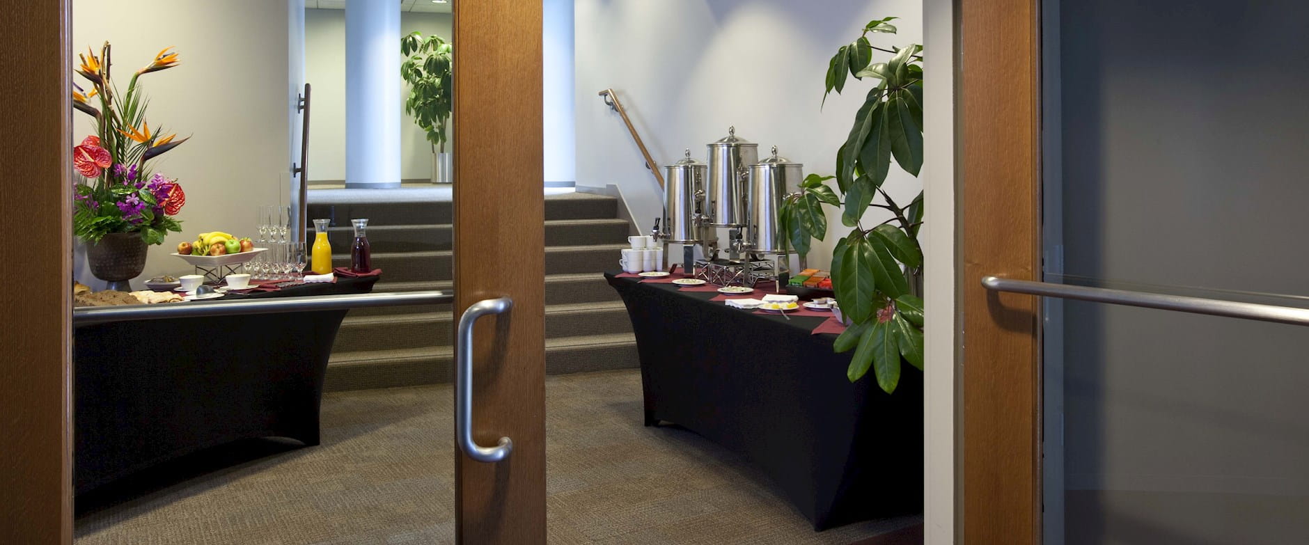 The foyer of one of the Gleacher Center's rooms with stairs leading up and a snack and coffee station along the walls